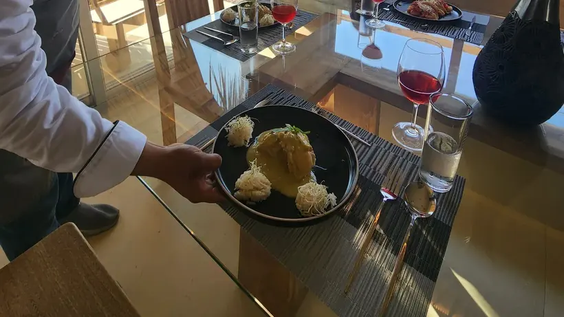 Chef serving a prepared nutritionist-optimized meal at the villa dining table