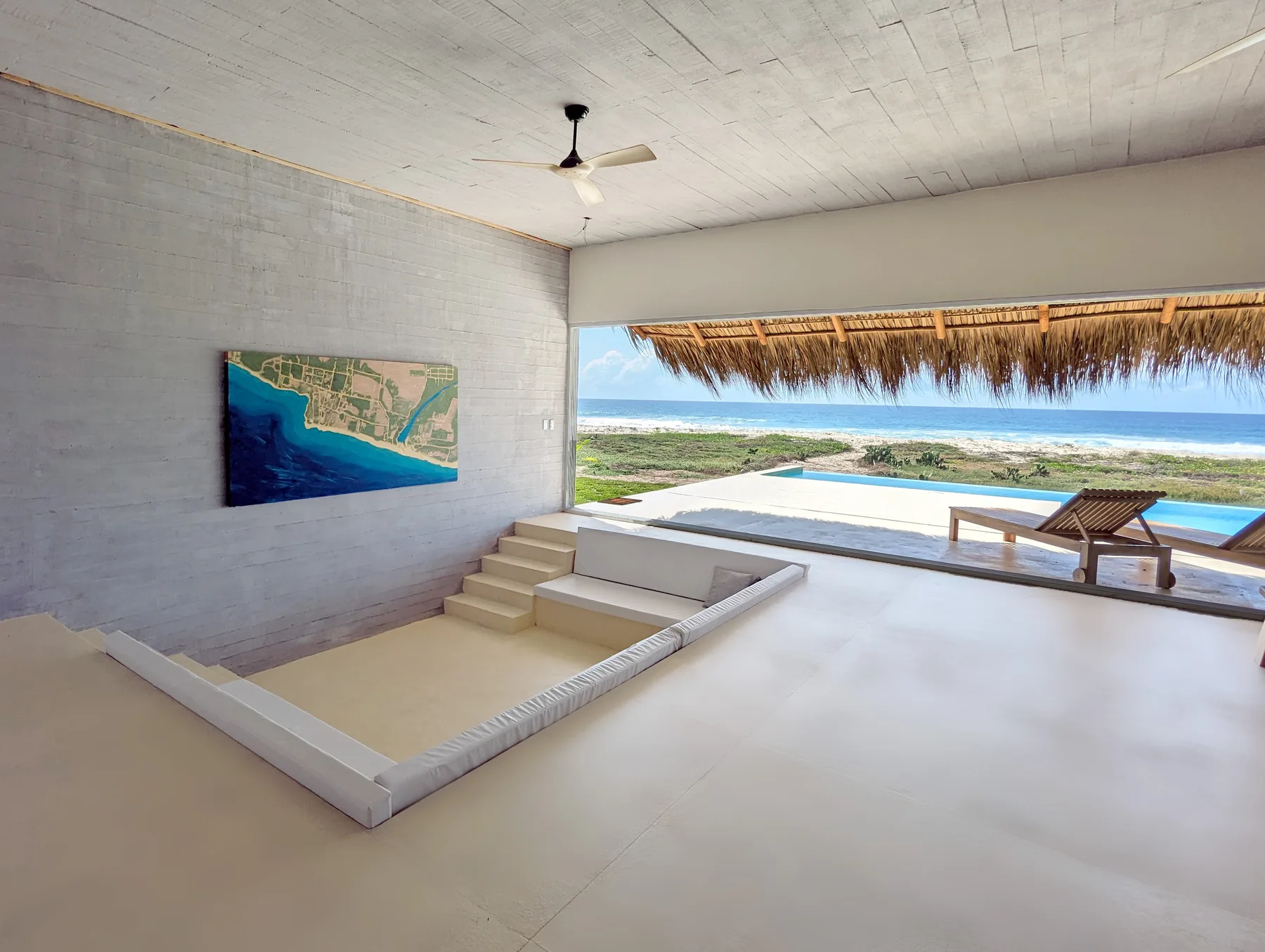 Wide villa interior with pool, lounge chair, and Pacific ocean view